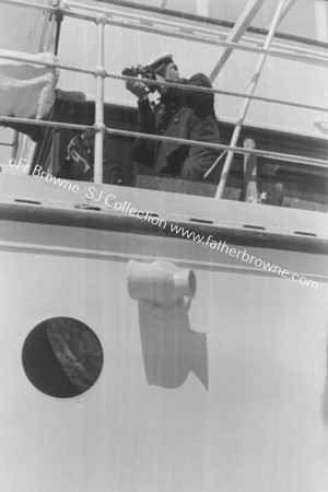 MID-DAY ON THE BRIDGE:OFFICER (TAKING BEARINGS) ON THE BRIDGE